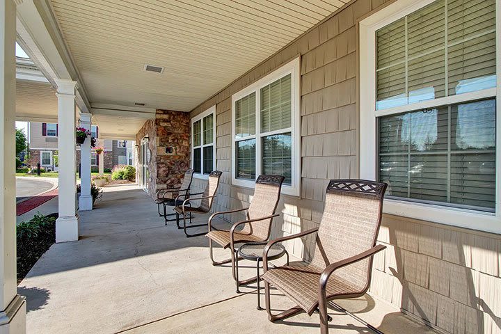 Covered porch with chairs outside apartment building